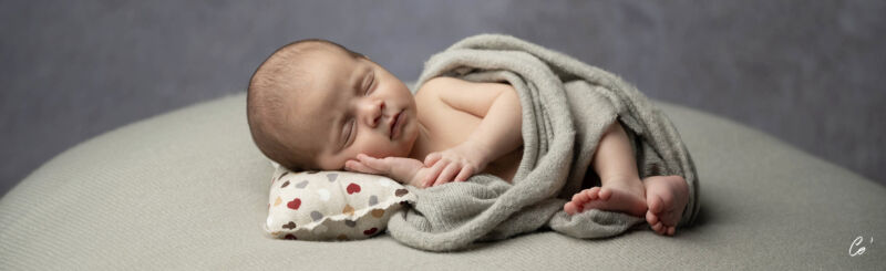 nouveau-né allongé sur une couverture et un petit coussin, main sous la tête